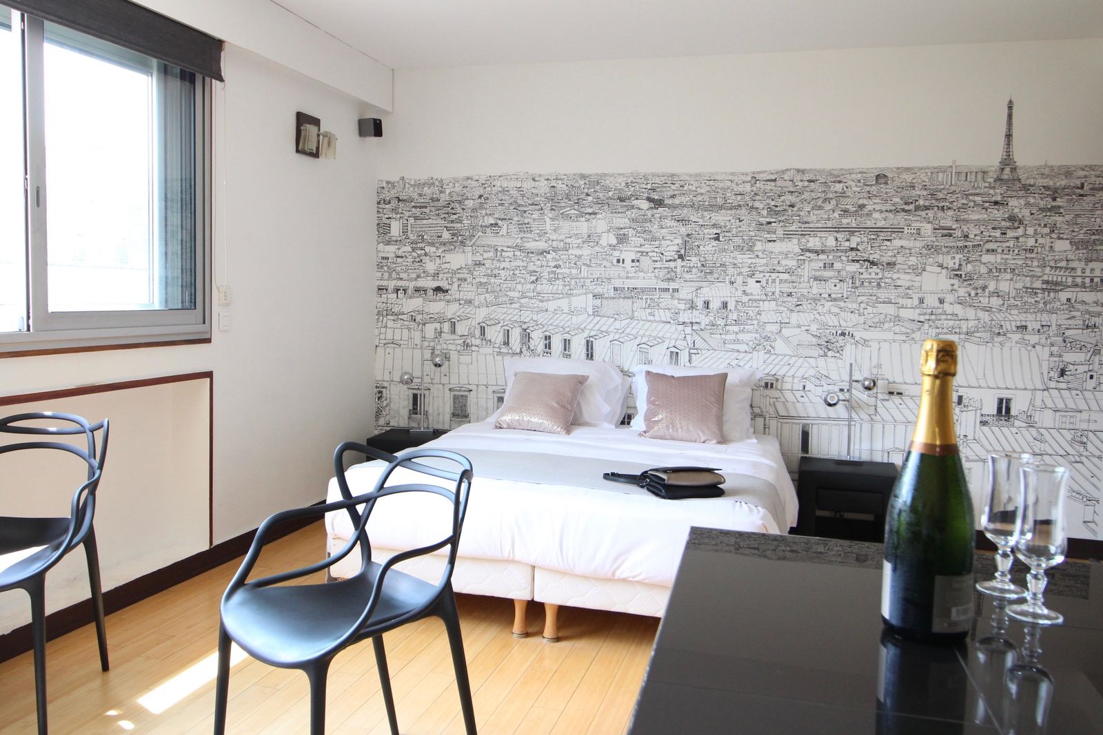 Close-up of bed with Eiffel Tower wall mural and champagne glasses on the nightstand