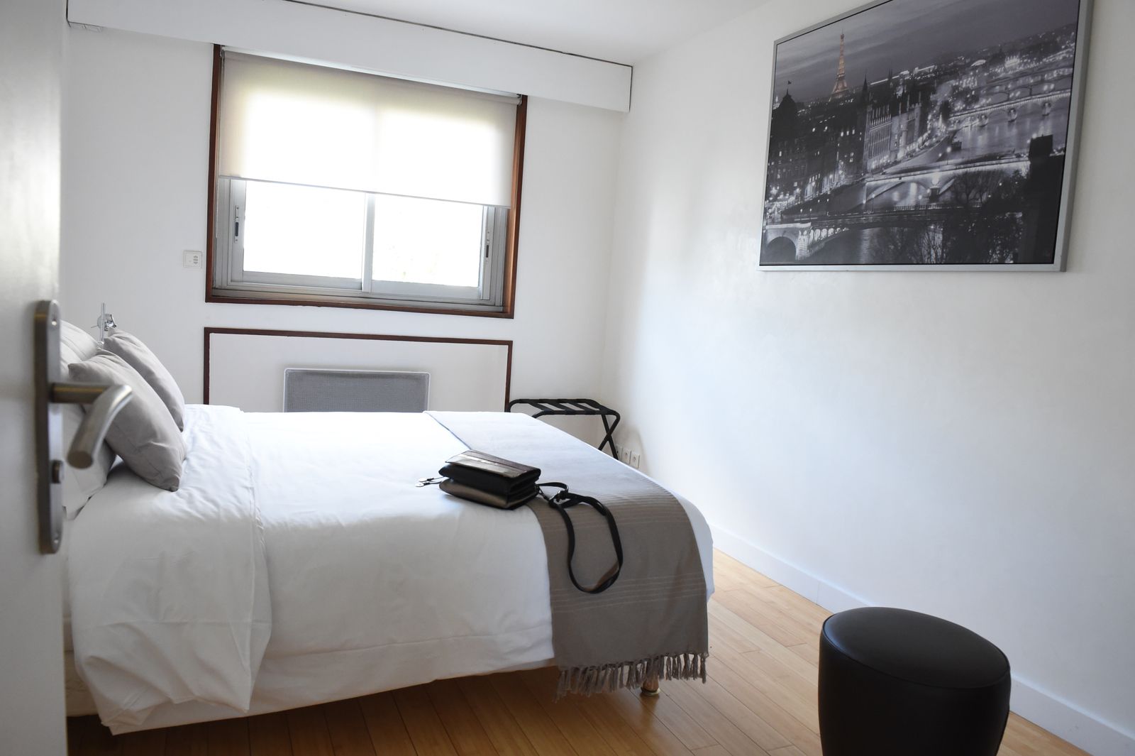 Chambre avec lit blanc et photo du pont de Paris