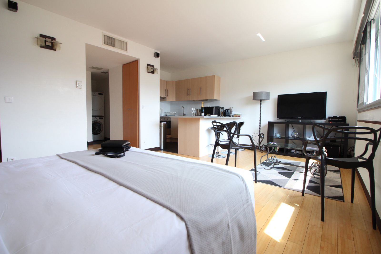 Vue large du studio avec cuisine, TV et parquet