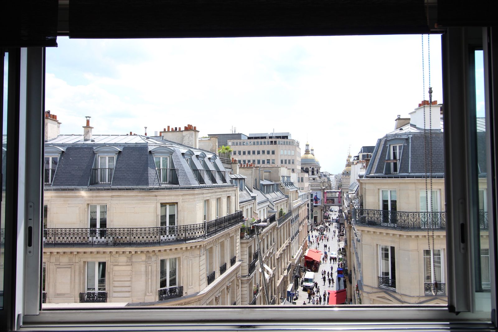 View from apartment window onto classic Haussmannian boulevard with Parisian architecture